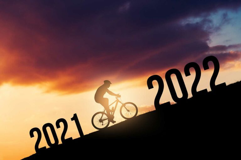 A cyclist biking up a hill. the cyclist is between the year 2021 and 2022.
