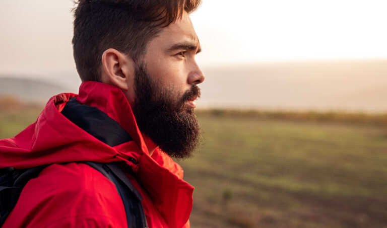A bearded male hiker in red looking to the side.