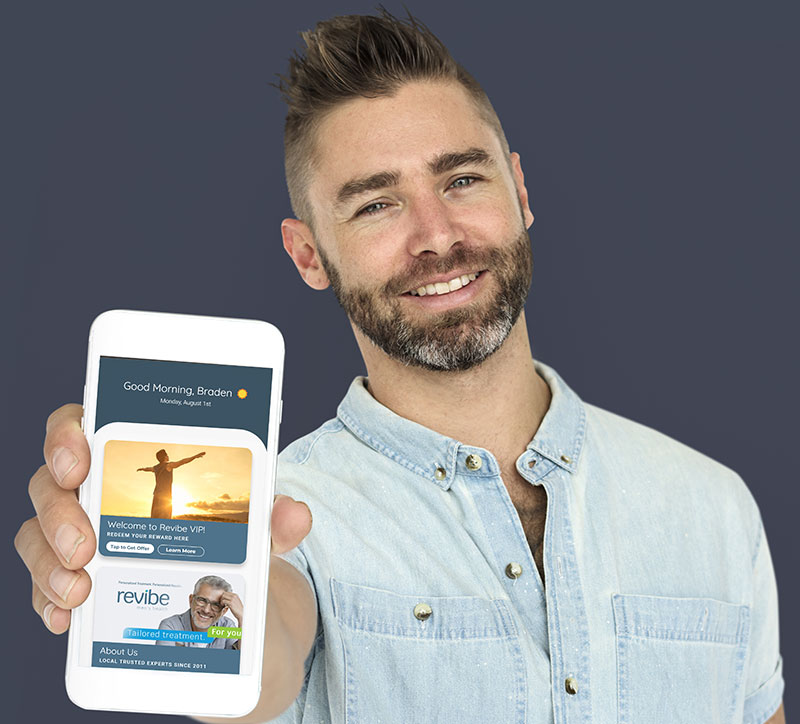 A man holding a smart phone with the Revibe app shown.